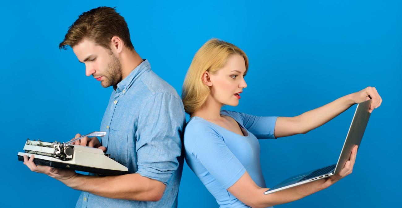 Mann und Frau stehen vor einem blauen Hintergrund, Rücken an Rücken. Die Frau bestaunt ihr neues Notebook, während der Mann etwas verwirrt auf die mechanische Schreibmaschine in seinen Händen blickt. Ein Symbolbild für App-Modernisierung.