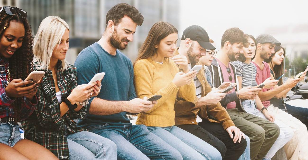 Eine Reihe von Menschen blickt auf ihr Smartphone, ein Symbolbild für Apps für Kommunen und die Nutzung der Bürger-App im Alltag.