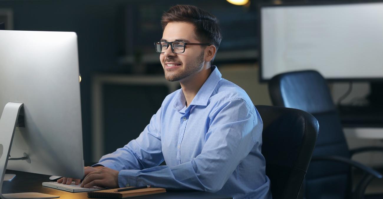 Ein junger, dynamischer Programmierer sitzt euphorisch vor seinem Computer bei der B3S-Softwareentwicklung.