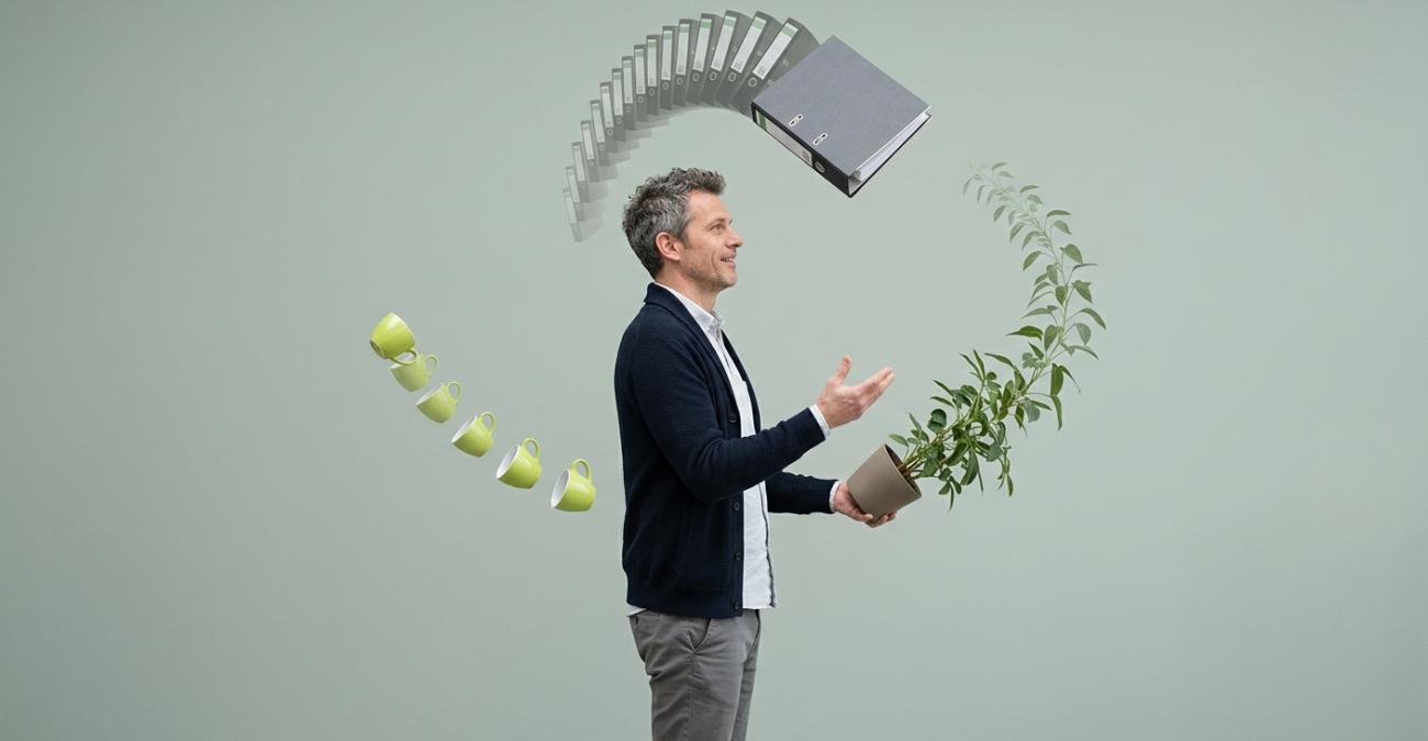 Ein Mann im dunkelblauen Cardigan jongliert einen Ordner, eine Topfpflanze und eine gelbgrüne Tasse, hinter Ordner und Tasse stehen Kopien in unterschiedlich dichten Abständen in der Luft. Sinnbild für einen Backup-Plan, der jedem System seinen eigenen Sicherungsrhythmus gibt.