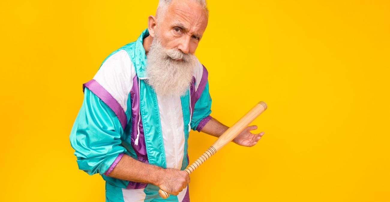 Ein älterer Herr im Trainingsanzug mit einem Baseballschläger in der Hand blickt herausfordernd in die Kamera. Das Bild ist witzig gestaltet. Es ist ein augenzwinerndes Symbolbild für Berechtigungsmanagement.