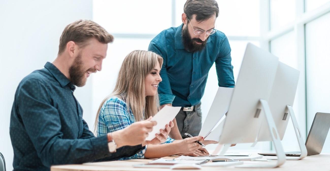 Lächelnde Mitarbeiter prüfen gemeinsam Finanzunterlagen am Schreibtisch – ein Sinnbild dafür, wie ein DSGVO-konformes Löschkonzept Aufbewahrung und Löschfristen in Verwaltung und Mittelstand sicher im Griff behält.