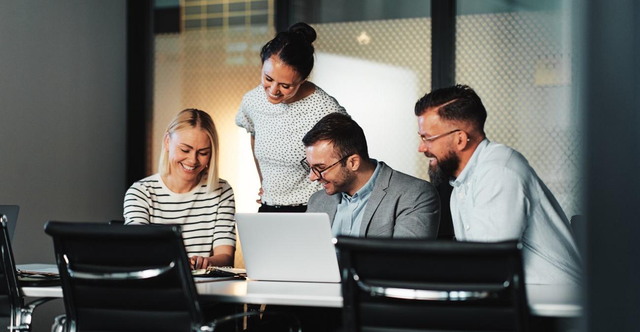 Im Konferenzraum der Verwaltung sitzen Digitalisierungsbeauftragte mit ihren Notizen vor einem Notebook. Sie sind fröhlich und planen vergnügt die Ablösung einer Fachanwendung.