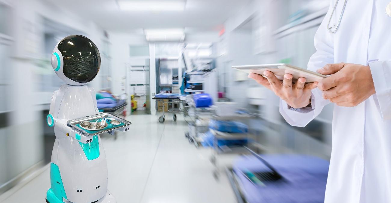 Roboter-Assistent unterstützt einen Arzt mit einem Tablet bei der Übermittlung medizinischer Daten im Krankenhaus – Sinnbild für Health IT Compliance im Umgang mit       digitaler Medizintechnik.