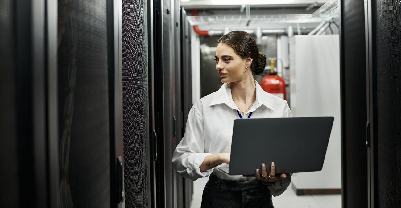 Ein heller Serverraum im Keller. Eine junge, selbstbewusste Programmiererin schreitet mit ihrem Notebook durch die Serverschränke. Sie will die moderne IT-Infrastruktur überwachen.