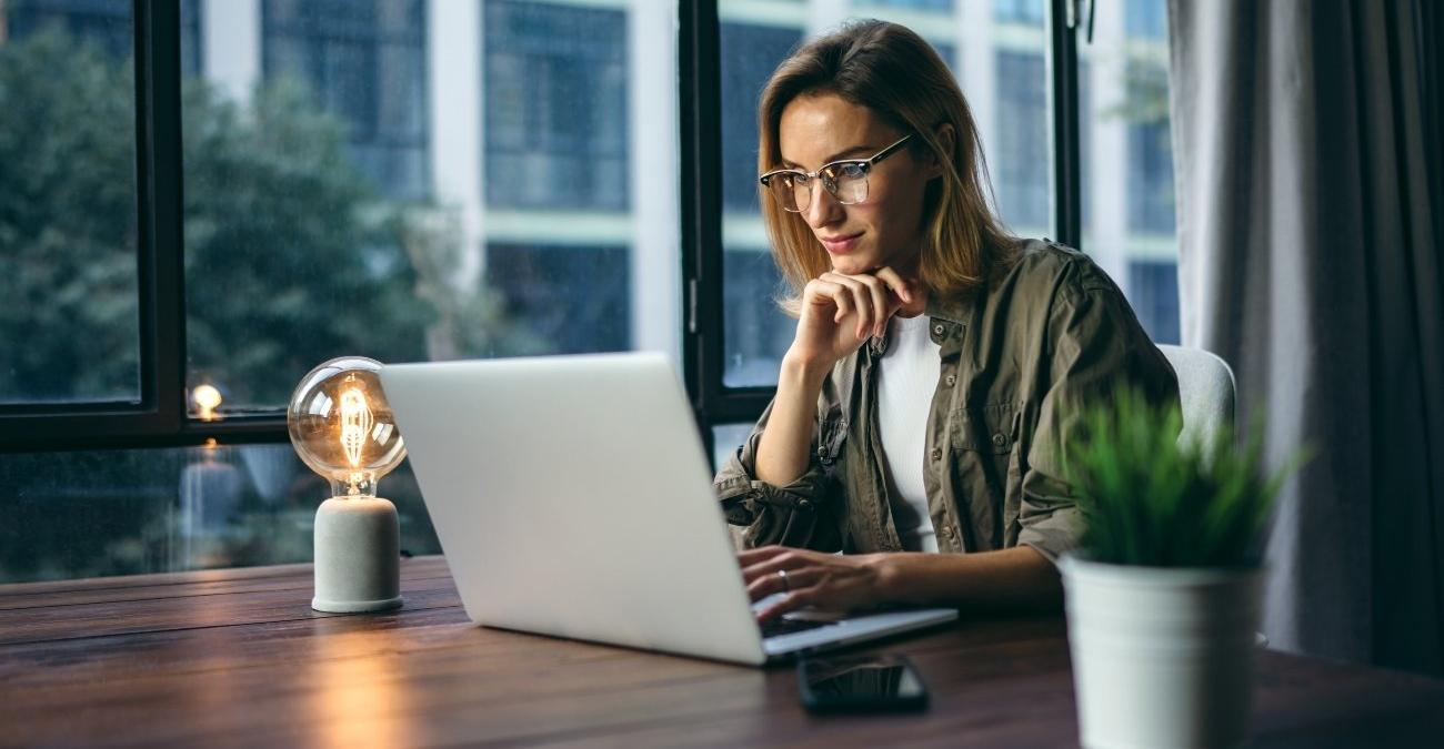 Eine junge Frau arbeitet an ihrem Laptop und verbindet sich über den Rechner mit dem Internet. Ein Symbolbild für die KI-Anbindung an Fachverfahren, bei der bestehende Anwendungen über Schnittstellen mit künstlicher Intelligenz verknüpft werden.
