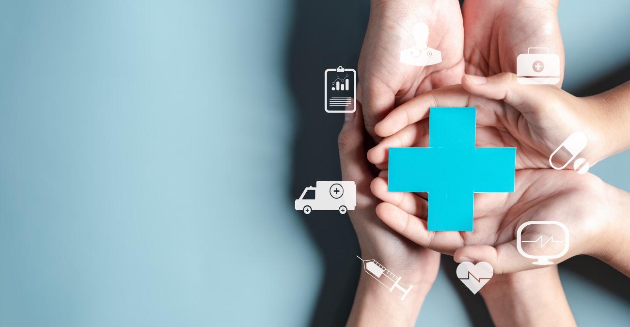 Sechs Hände liegen übereinander, die Handflächen nach oben. Sie halten ein blaues Kreuz. Darum herum schwirren Symbole aus der Medizin, symbolisch für KIM: Kommunikation im Medizinwesen.