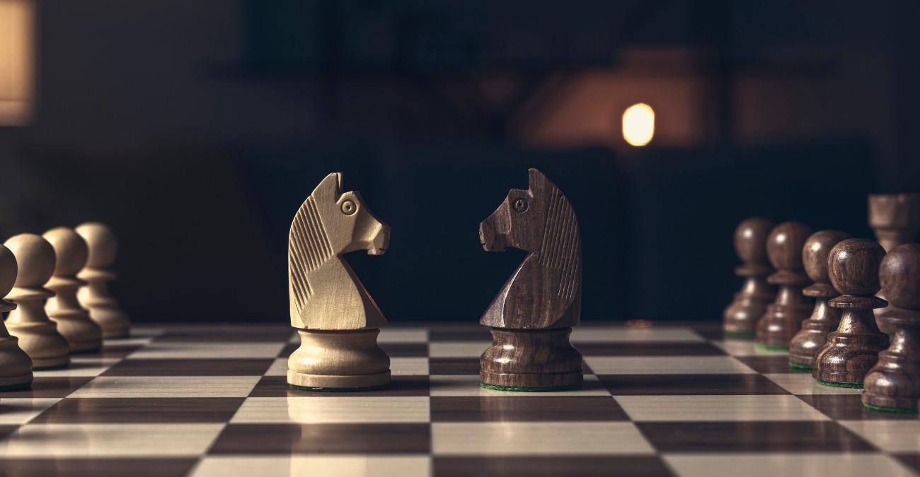 Auf einem Schachbrett stehen sich ein weißer und ein schwarzer Springer gegenüber, symbolisch für Laravel vs Symfony.