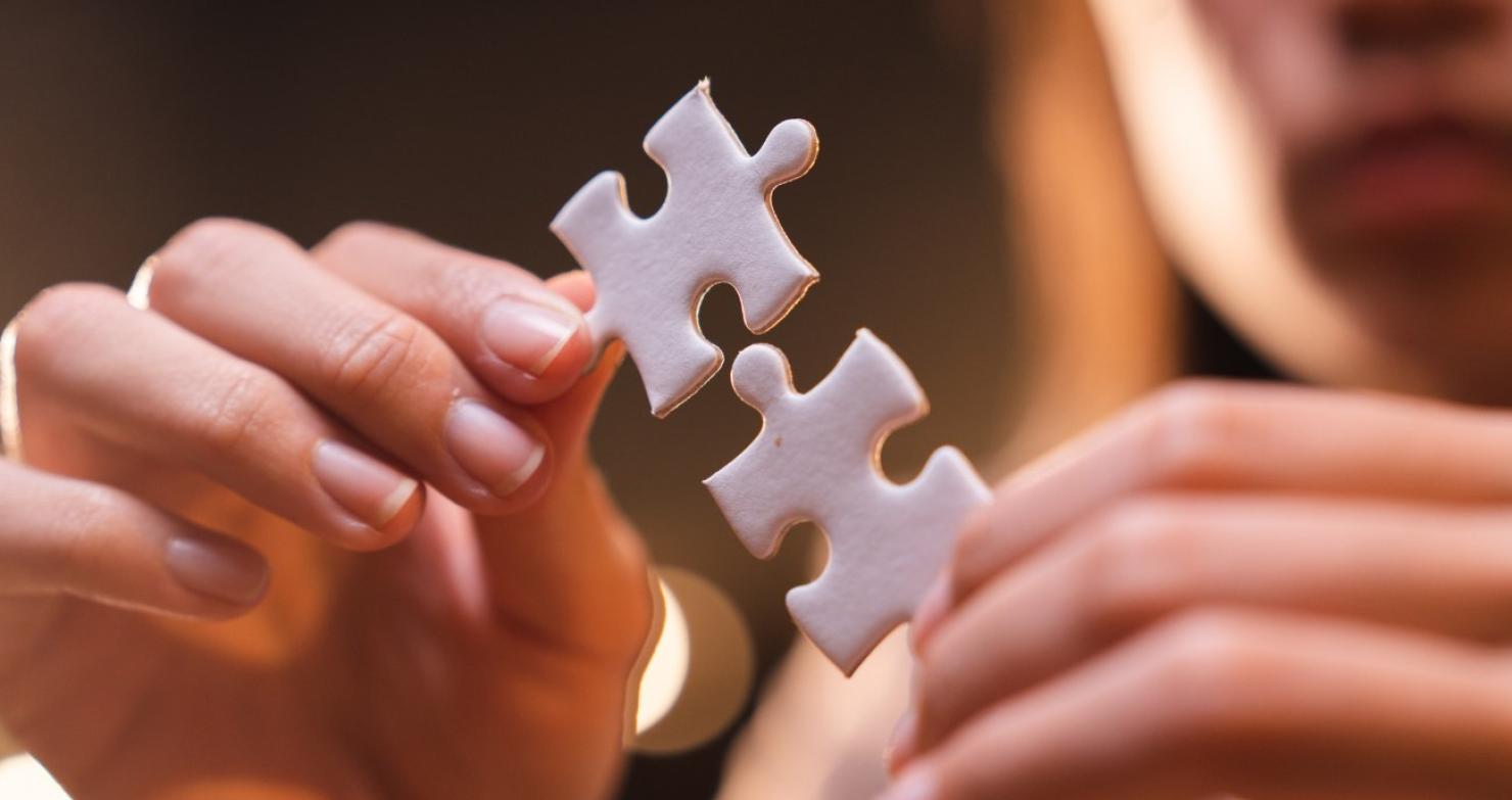 Zwei Hände fügen zwei Puzzleteile zusammen. Ein Sinnbild für Middleware-Software als Verbindung getrennter Anwendungen zu einem stimmigen Ganzen.
