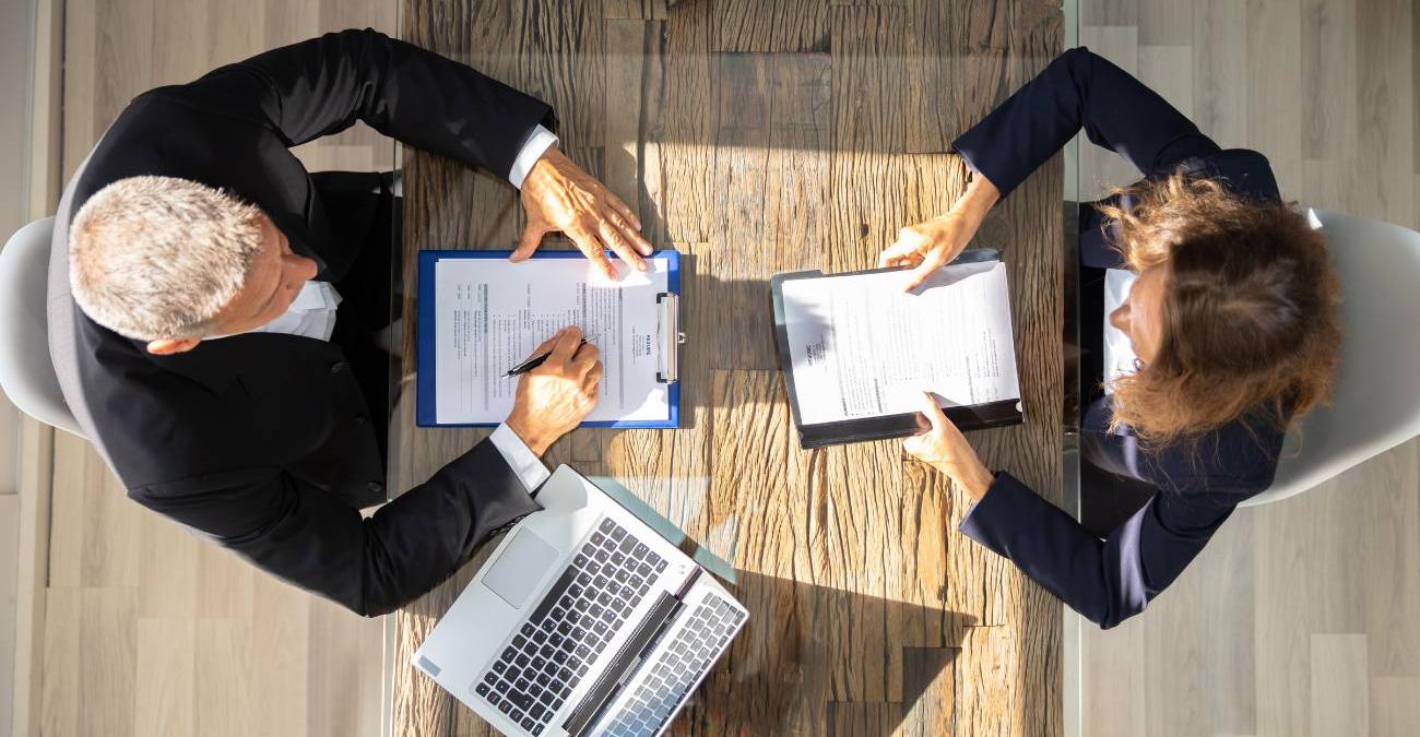 Zwei Personen prüfen einen Softwarepflegevertrag am Schreibtisch.