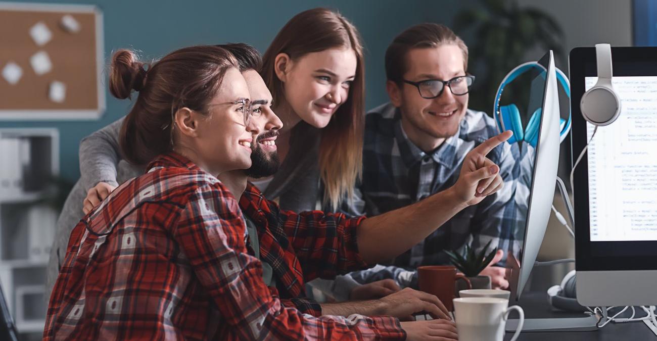 Ein Entwicklerteam in einem modernen Berliner Büro arbeitet gemeinsam an der Wartung einer Softwareanwendung.