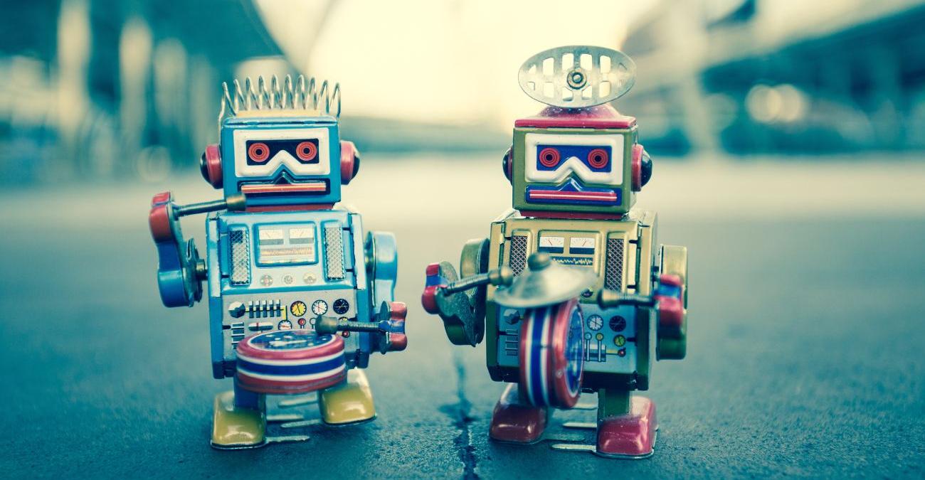 Zwei kleine bunte Roboter stehen auf der Straße und musizieren mit Trommeln und Schellen. Ein Symbolbild für das PHP-Framework Symfony.