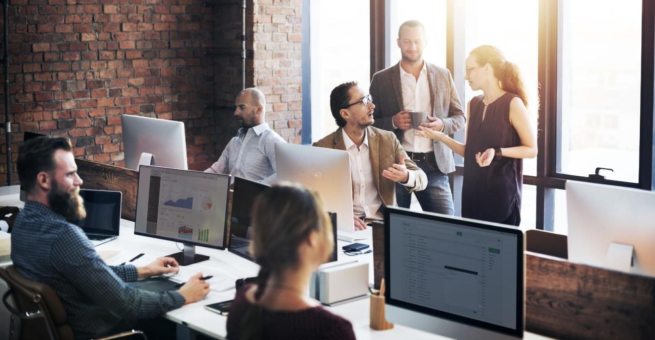 Ein Team sitzt im Büro an Rechnern und arbeitet mit der Intranet Software.