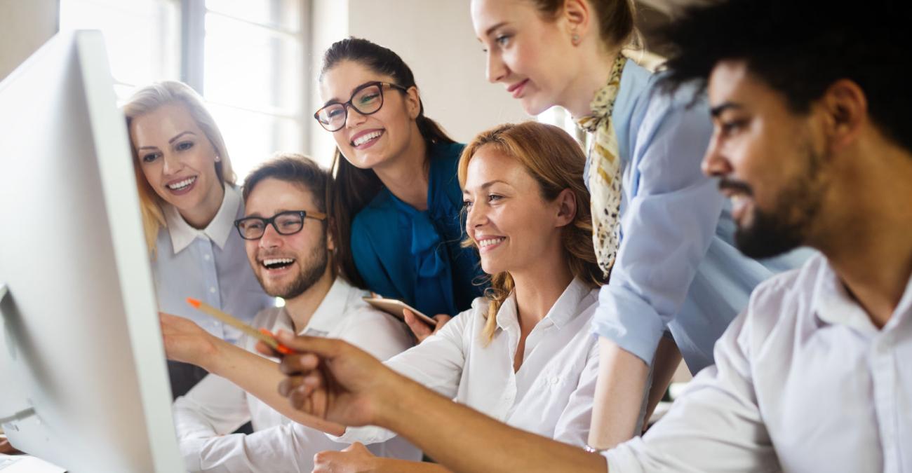 Mitarbeiter*innen einer Internetagentur arbeiten an einem Projekt und schauen gemeinsam auf einen Bildschirm.