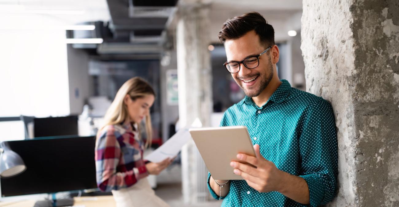 Ein Mensch mit Tablet, ein anderer Mensch mit Unterlagen im Büro