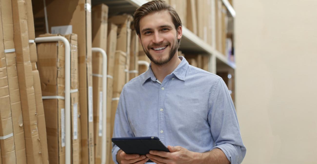 Mann führt Inventarliste mit einem Tablet vor einem Regal