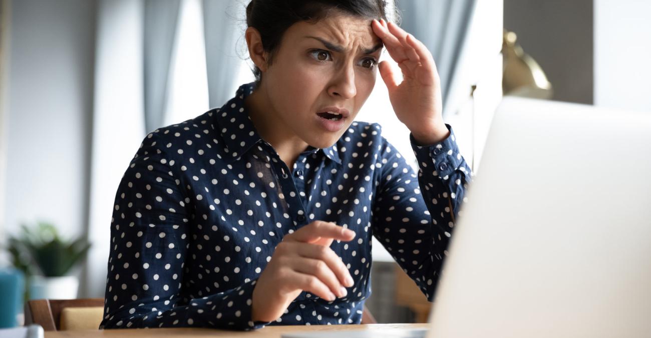 Verzweifelte Frau sitzt vor einem PC am Schreibtisch