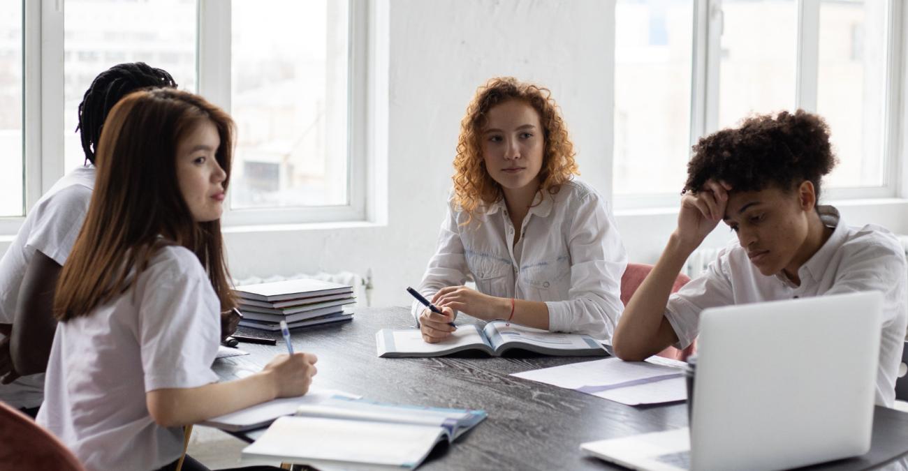 Vier Frauen sitzen am Tisch und schauen auf einen Bildschirm