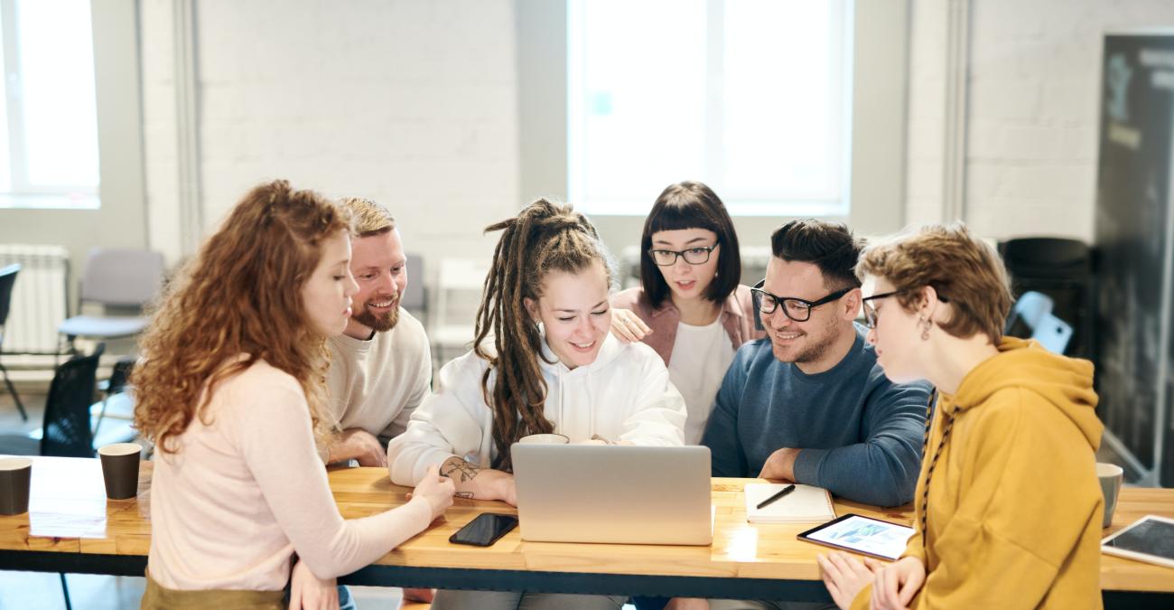 Menschen schauen gemeinsam auf einen PC am Schreibtsich