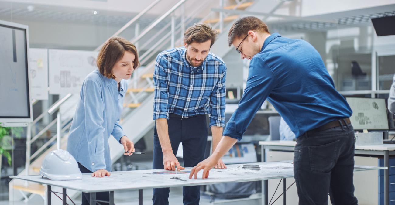 Zwei Männer und eine Frau planen an einem Tisch Softwareentwicklung