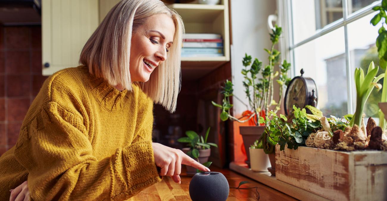 Ältere Dame nutzt modernen Lautsprecher. Sie ist begeistert von der Technologie von Google Little Signals.