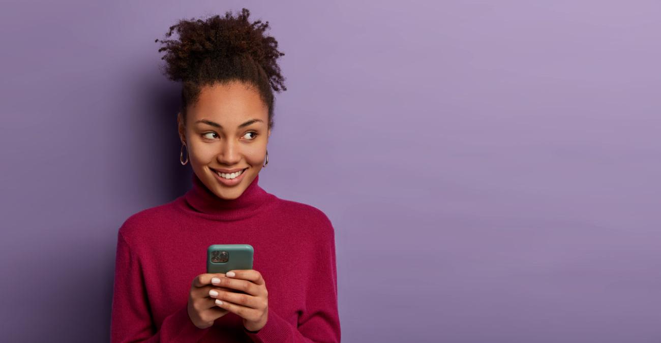 Junge Frau mit einem Handy. Sie freut sich über die gute Mobilfunknetzabdeckung.