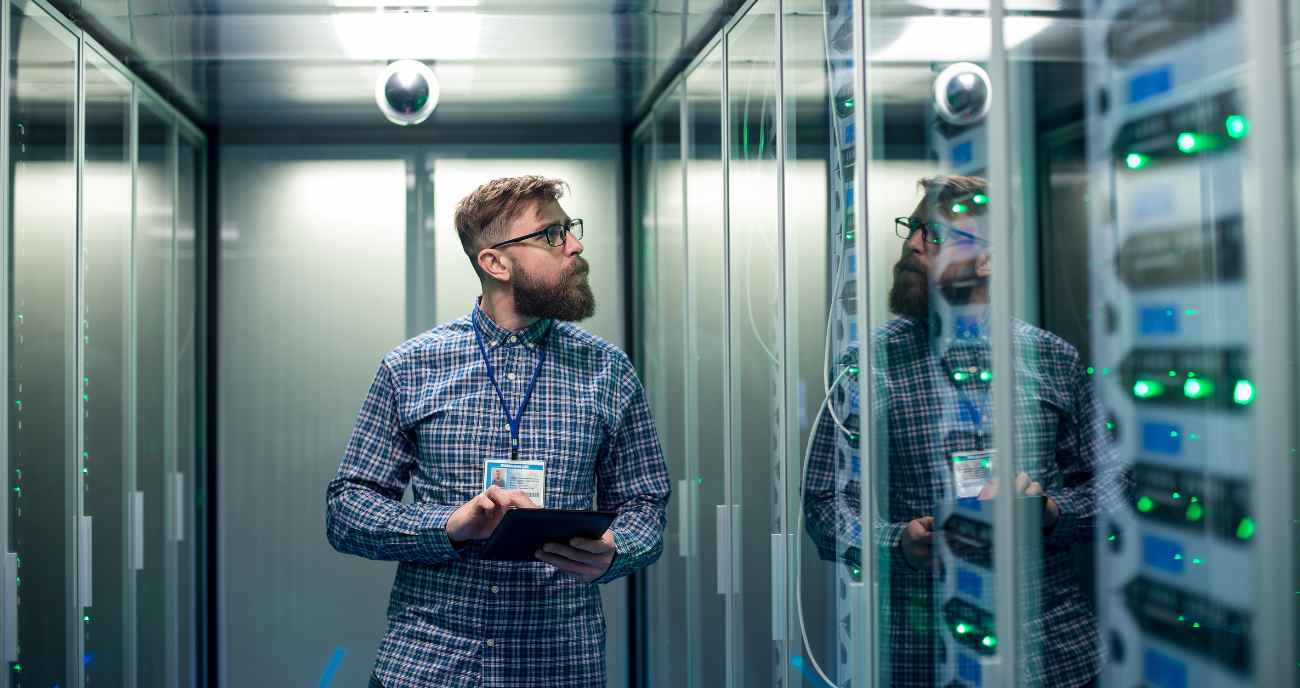 Ein Informatiker steht im Serverraum vor einem Oline-Datenspeicher. Dieser ist dezentral und bietet daher Datenschutz für Unternehmen.