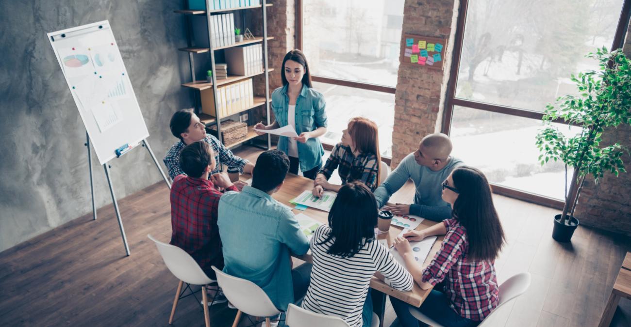 Eine Agentur bespricht das Konzept für das Monitoring für ihre Kunden in einem Meeting-Raum an einem Tisch mit Flipchart.