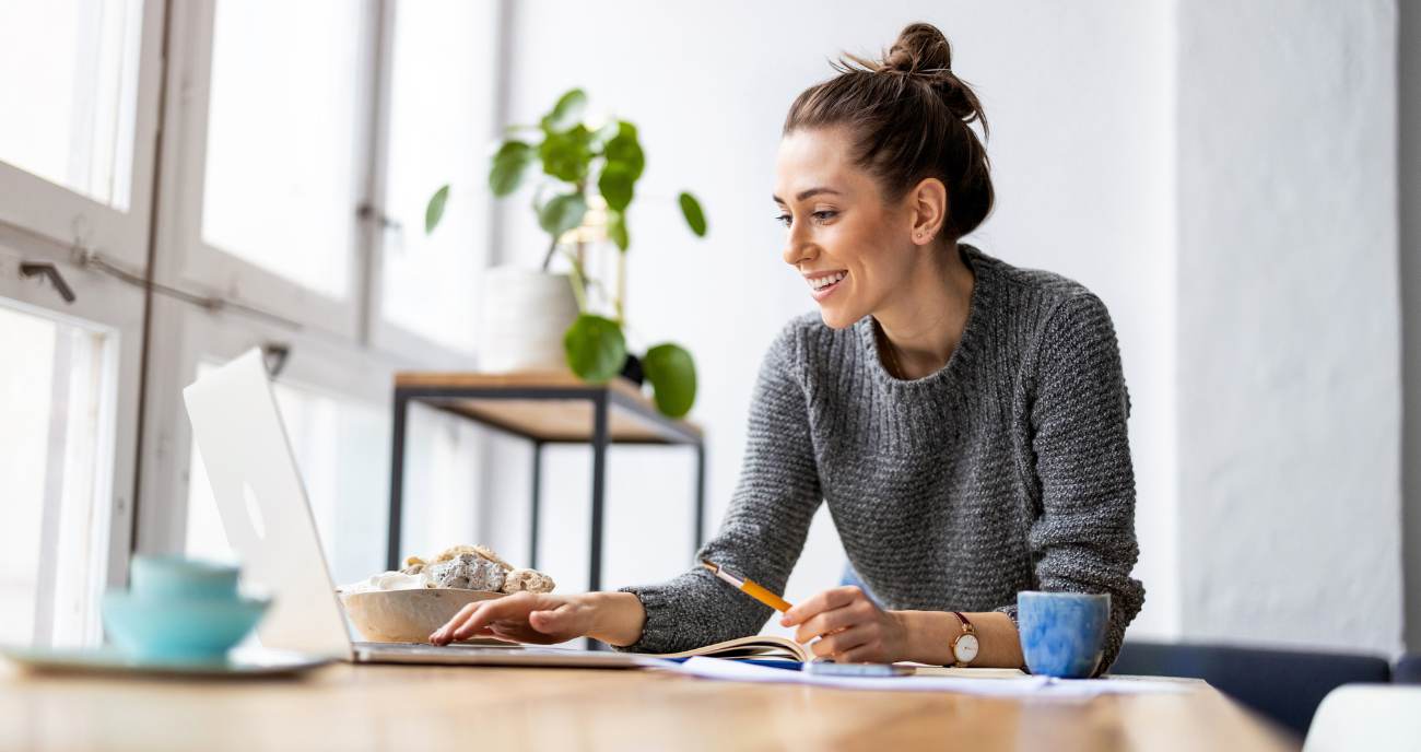 Eine junge Frau sitzt im hellen Büro an ihrem Notebook. Sie betreibt Website-Wartung.