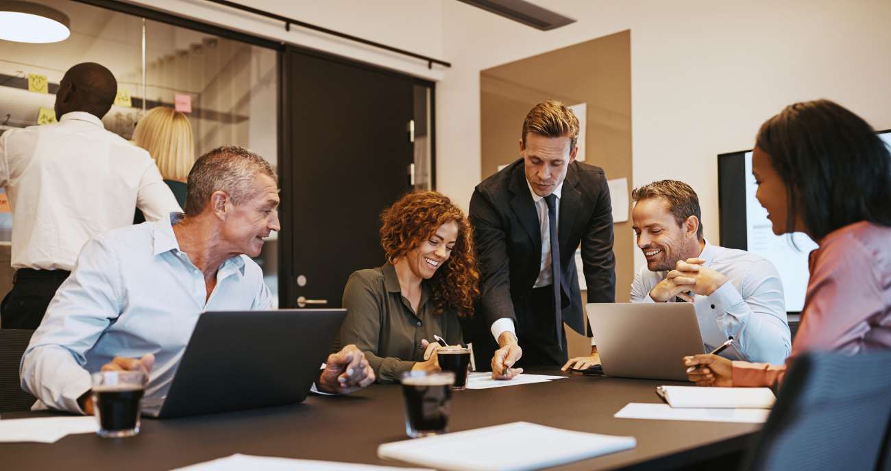 Ein modernes Office. Laravel-Entwickler und Entwicklerinnen diskutieren euphorisch über eine Software.