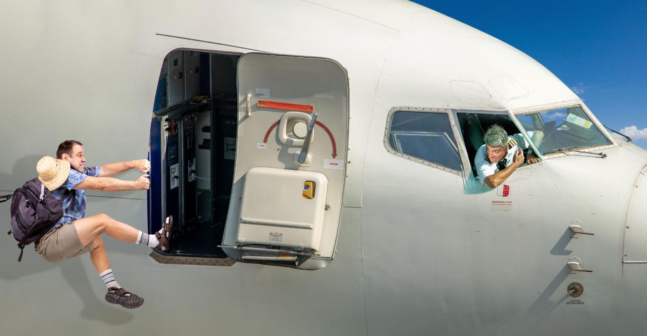 Mann ist aus Flugzeug gefallen und hält sich an der offenen Tür der Kabine fest. Eine Metapher für Cybersicherheit.