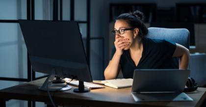 Junge Frau sitzt erschrocken der ihrem Notebook. Der Grund: Micrisoft-Outlook-Konto-gehackt.