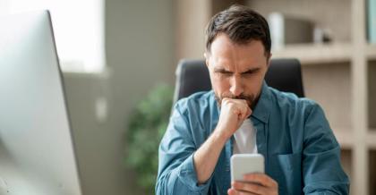 Ein Mann sitzt im Büro. Er blickt nachdenklich auf dein Handy und scrollt durch seinen Telegram Chat.