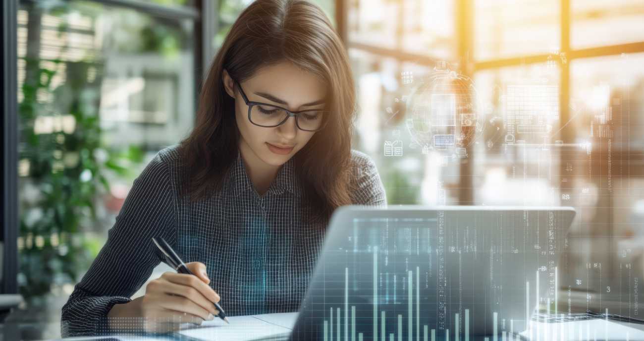 Eine dynamische Frau sitzt im Büro an ihrem Notebook. Sie erstellt ein Konzept für die IT-Security im Unternehmen.