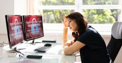 Eine Mitarbeiterin sitzt im Office frustriert an ihrem Rechner. Das System ist lahmgelegt. Der Ransomware-Schutz wurde vernachlässigt.