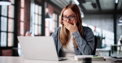 Eine Frau sitzt im Büro vor ihrem PC. Sie ist verzweifelt, da sie Opfer von Datendiebstahl wurde.