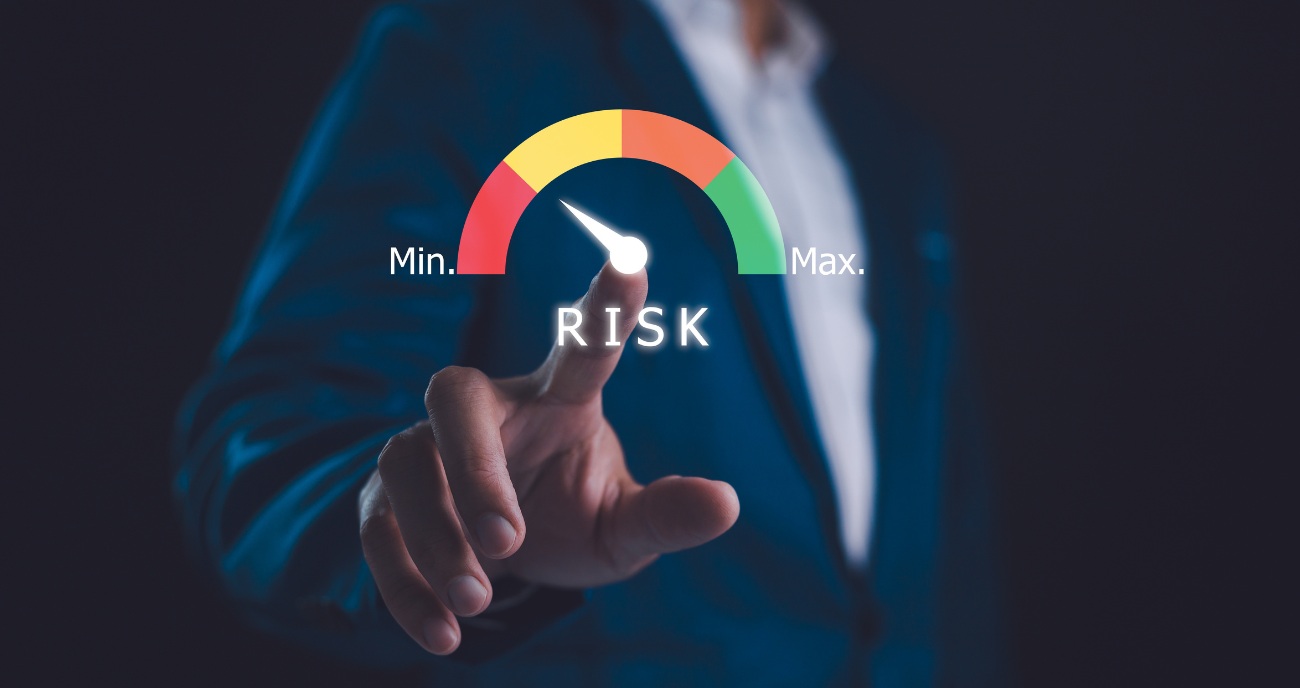 Die Hand eines Geschäftsmanns stellt einen imaginären Zeiger von Maximum Riks auf Minimum. Ein Symbolbild für die ISO-27001-Umsetzung in unserem Unternehmen.