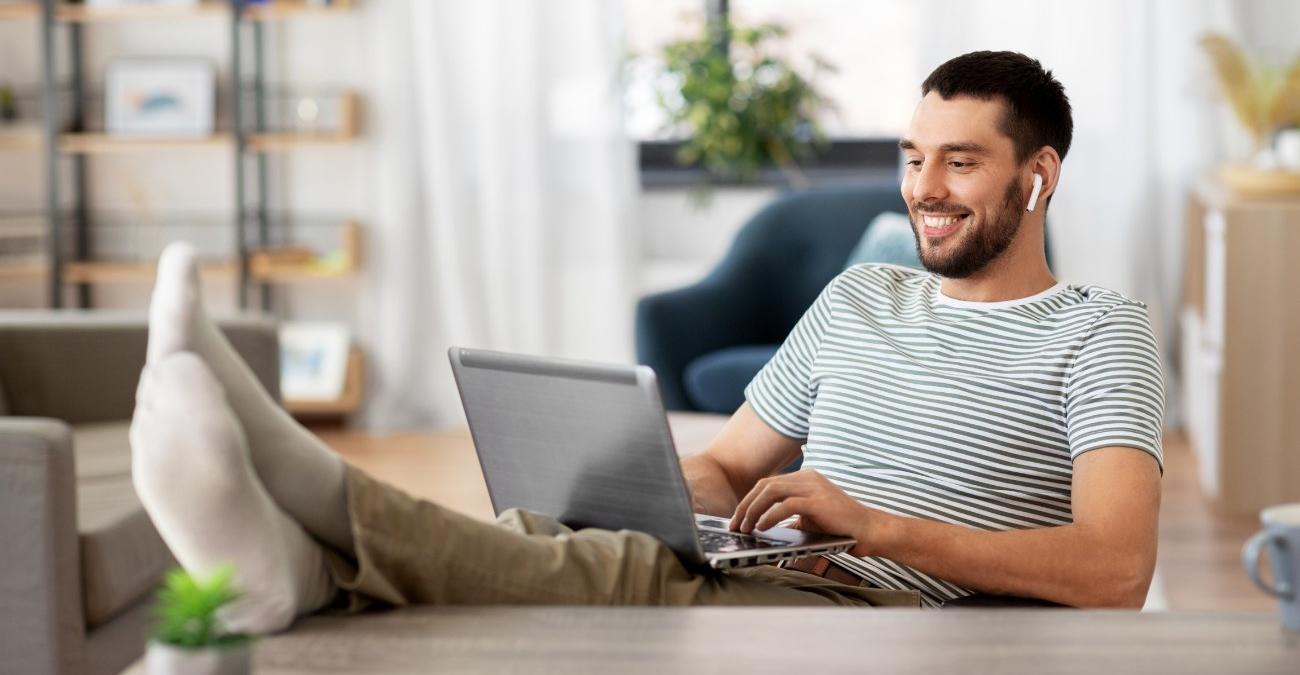 Ein junger Entwickler legt zuhause die Füße hoch und arbeitet entspannt mit dem Symfony Framework.