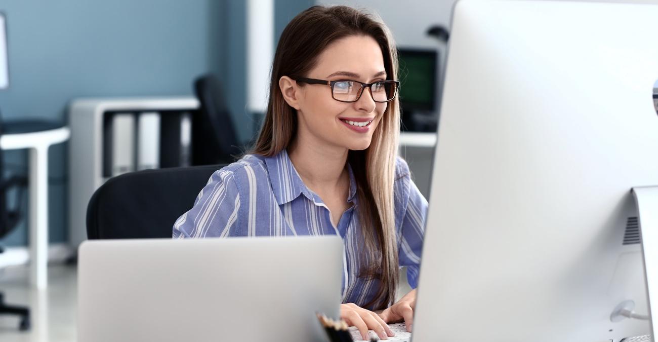 Ein Entwicklerin arbeitet gut gelaunt an ihrem Notebook an einem minimalistischen Code-Editor. Ein Symbolbild für das leichtgewichtige CodeIgniter-Framework.