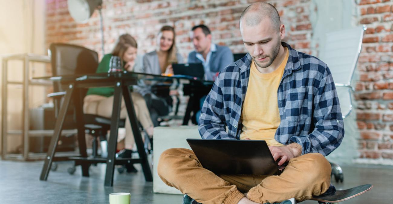 Ein Entwickler sitzt auf einem Skateboard und benutzt an seinem Laptop Laravel für die Erstellung einer responsive Website.