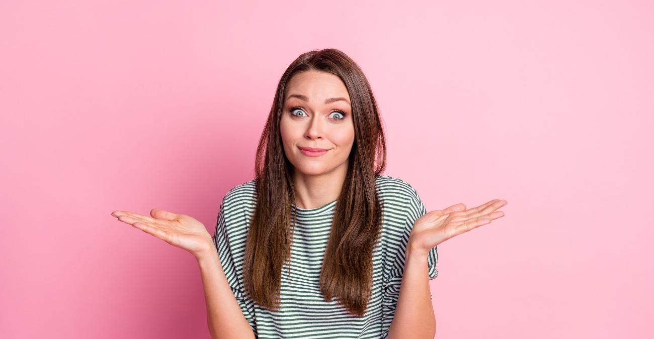 Eine junge Frau mit gestreiftem Shirt hebt ratlos beide Haende und blickt fragend in die Kamera — ein Sinnbild fuer die haeufige Verwechslung von Authentifizierung vs. Autorisierung.