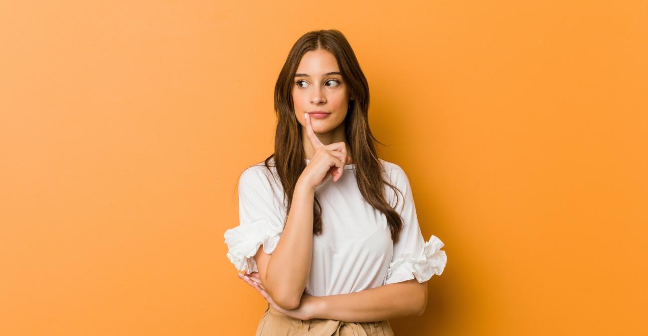 Eine junge Frau blickt mit zweifelndem, skeptischem Ausdruck zur Seite. Sinnbild für die kritischen Fragen, die eine Software Bill of Materials zu jeder eingesetzten Komponente beantwortet.