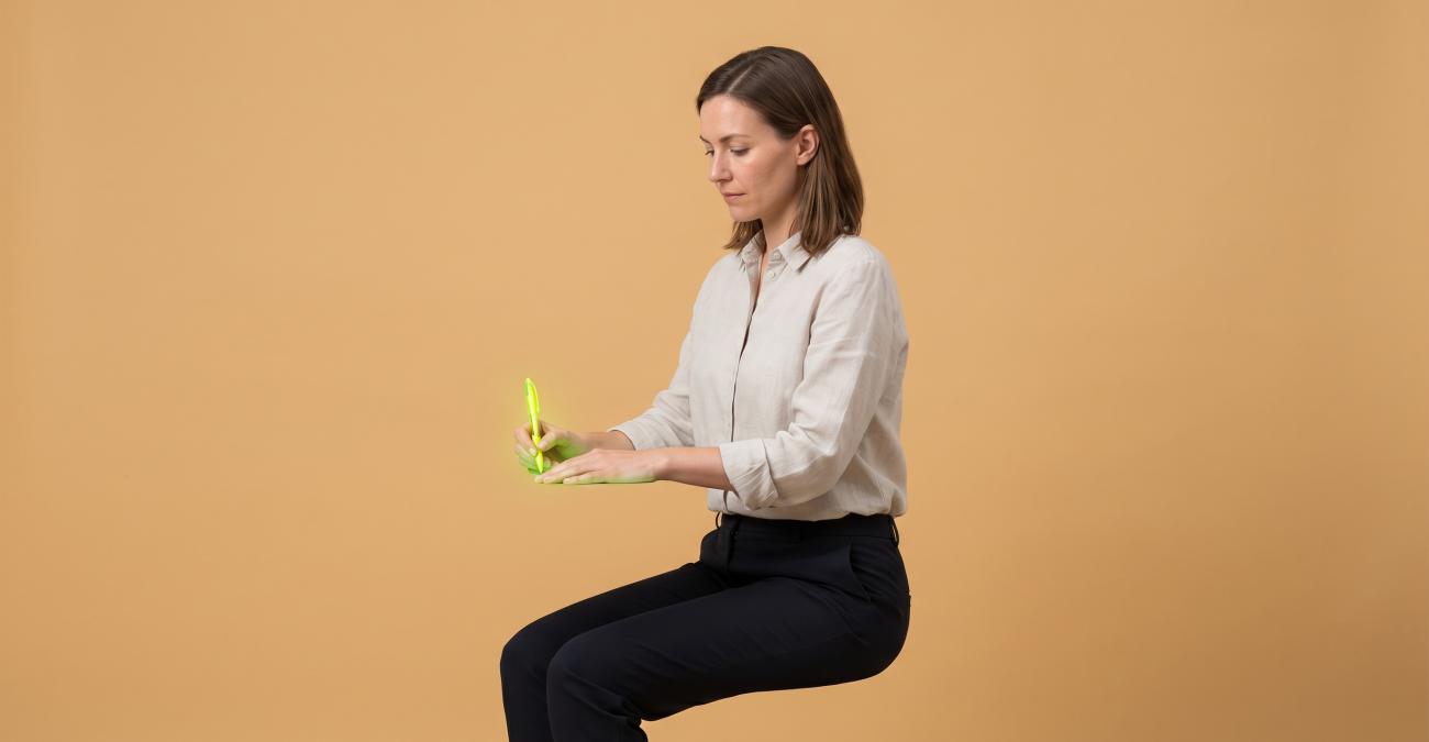 Eine Frau sitzt in exakter Arbeitshaltung mit Stift in der Hand, obwohl Stuhl und Schreibtisch fehlen. Sinnbild für die E-Akte, bei der die Papierakte wegfällt und der Vorgang bleibt.