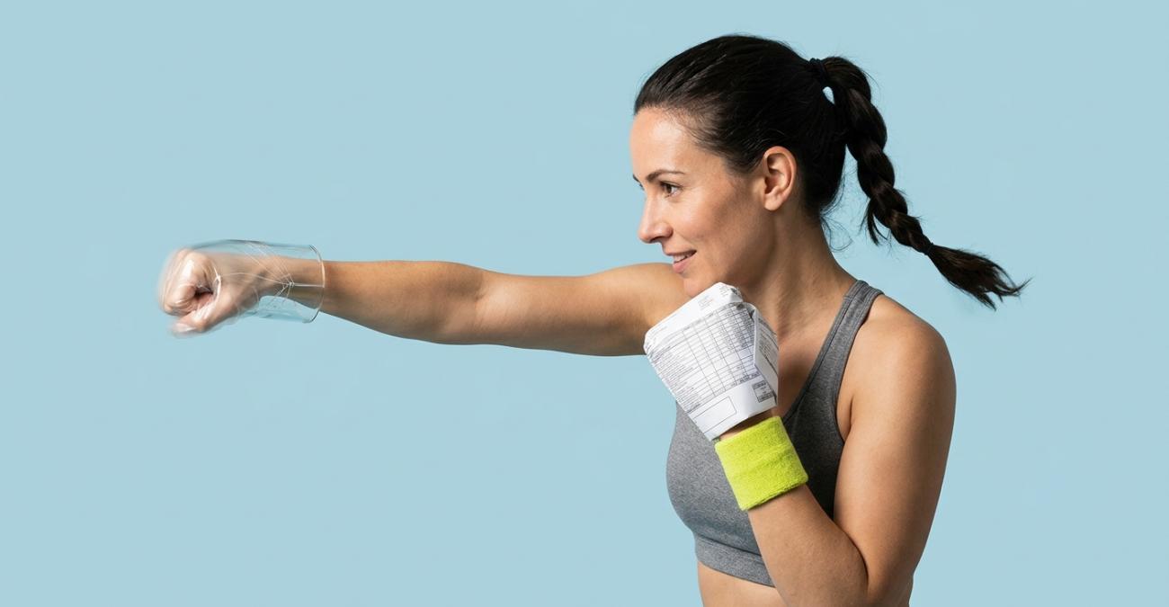 Eine Frau mit geflochtenem Zopf schlägt vor hellblauem Grund eine Gerade. Die schlagende Faust steckt in einem durchsichtigen Handschuh aus Glas, die Hand in Deckung in einem Handschuh aus gefaltetem Rechnungspapier, am Handgelenk trägt sie ein gelbgrünes Schweißband. Sinnbild für XRechnung oder ZUGFeRD: zwei Formate, die für dieselbe Rechnung antreten.